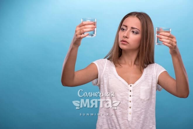 Девушка внимательно смотрит на стакан с водой, фото