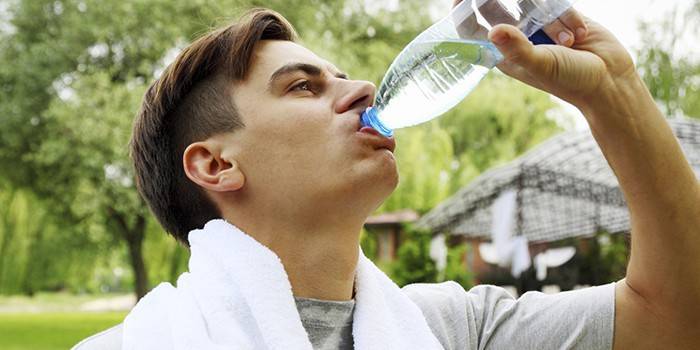 Мужчина пьет воду из бутылки